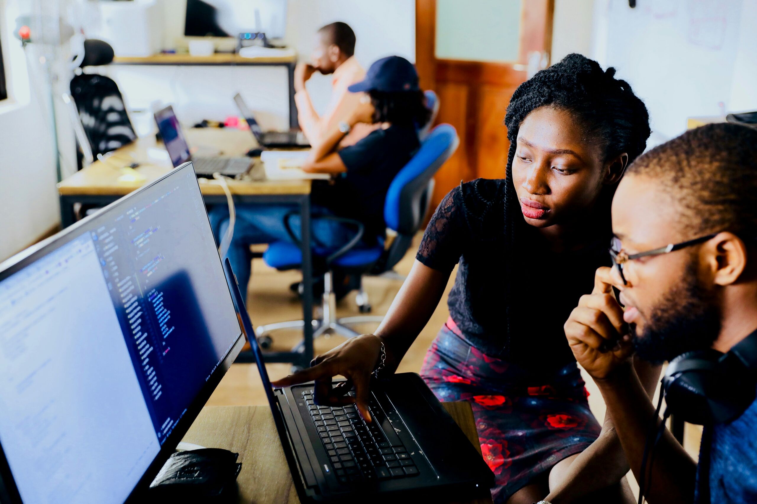 Two colleagues working together at a laptop in an open-plan office