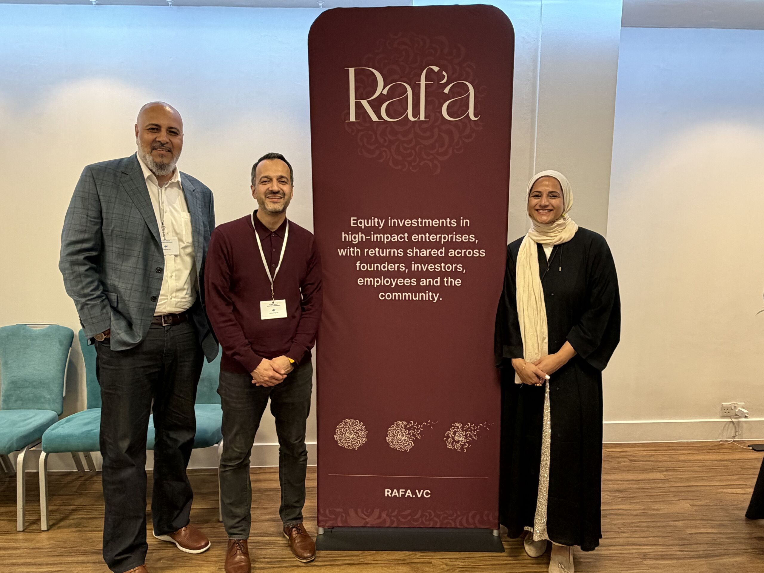 Sheeza Shah and two colleagues standing beside a Raf’a banner at an event