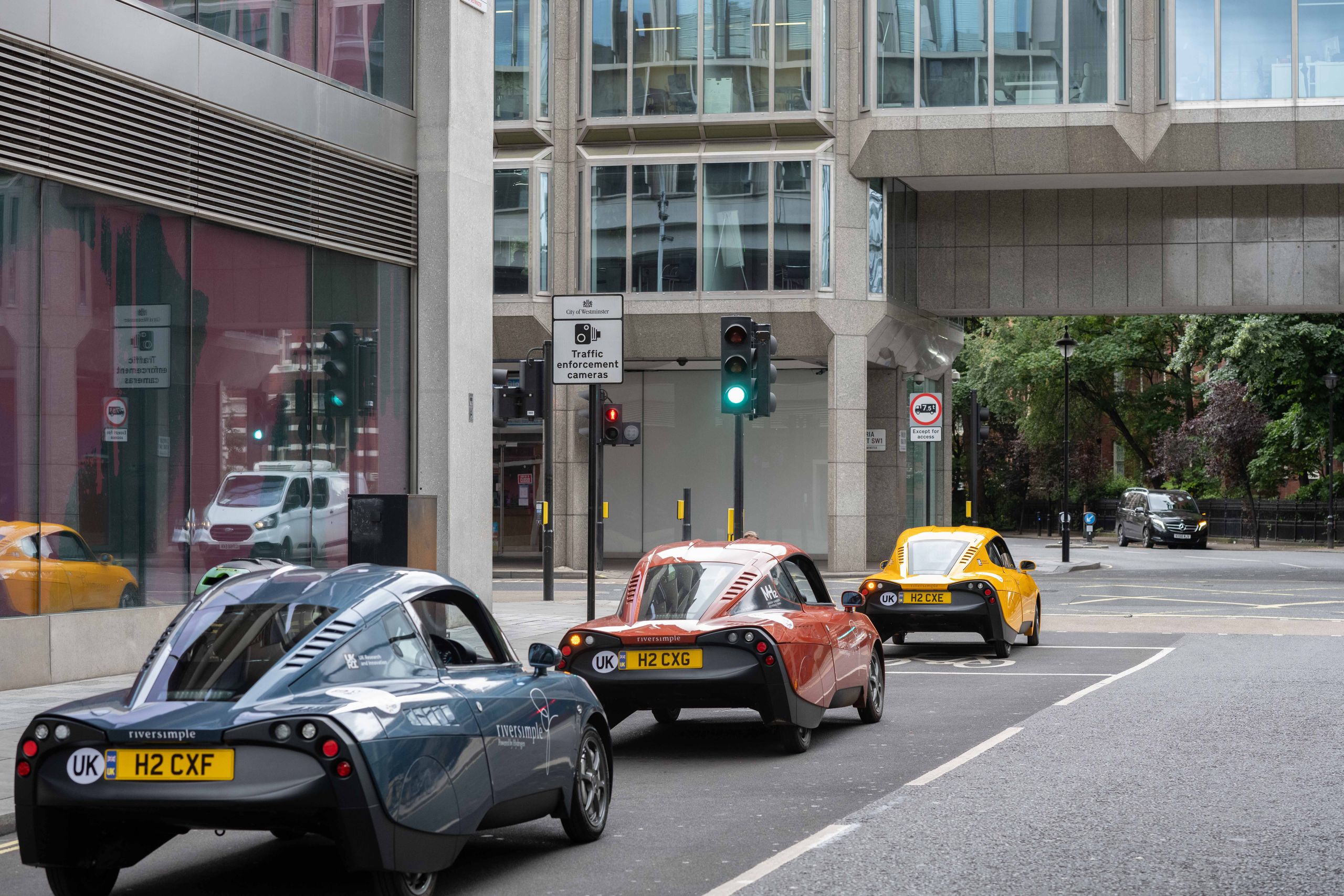 Three Riversimple Rasa hydrogen cars driving along a London street