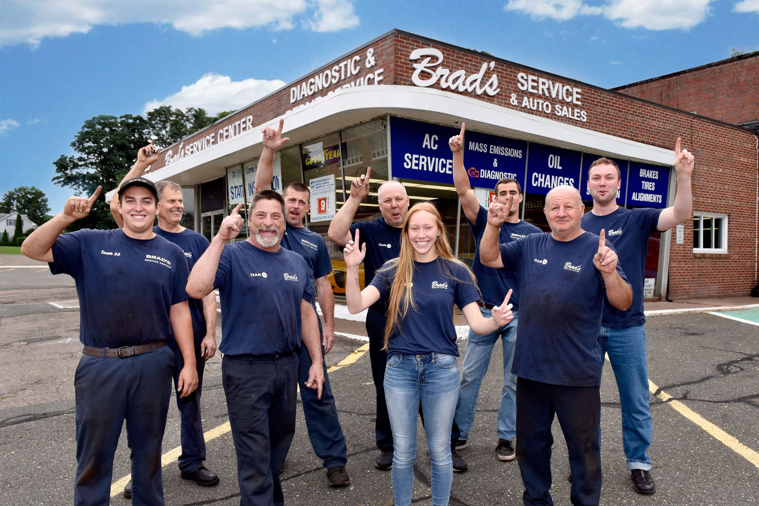 Mechanics in navy uniforms cheering outside Brad's Service Center